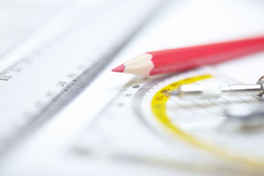Red pencil with compasses and rulers on a paper. Extremely close-up photo
