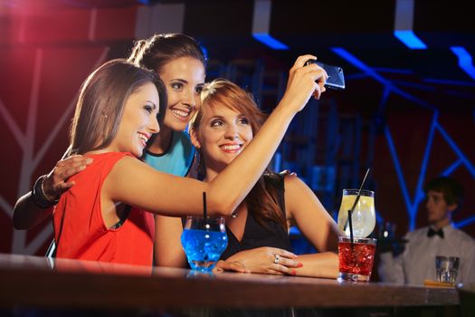 Three happy women at an nightclub party taking a self-portrait