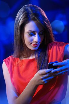 Young beautiful woman using a smartphone in a nightclub
