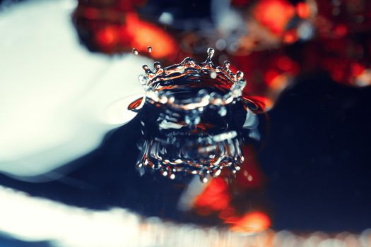 Extremely macro photo of the liquid drop falling on a wet colorful surface