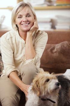 Portrait of a smiling senior woman sitting on couch with her dog