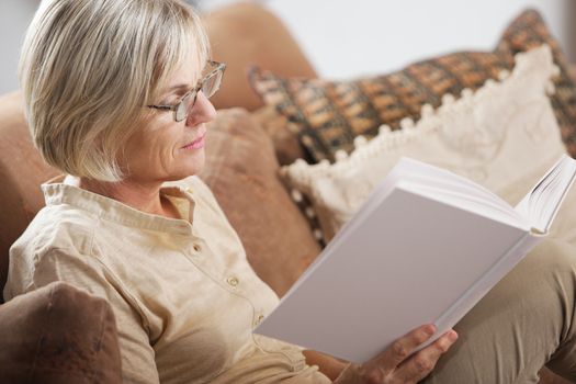 Pretty mature woman passing her time by reading a book 