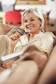 Pretty mature woman passing her time by reading a book 