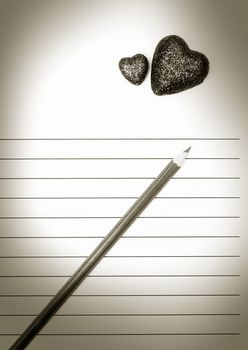 Pencil and two hearts on a blank love letter. Sepia colors added