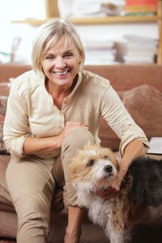 Portrait of a smiling senior woman sitting on couch with her dog