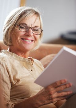 Smiling senior woman reading a book at home