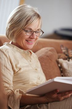 Smiling senior woman reading a book at home