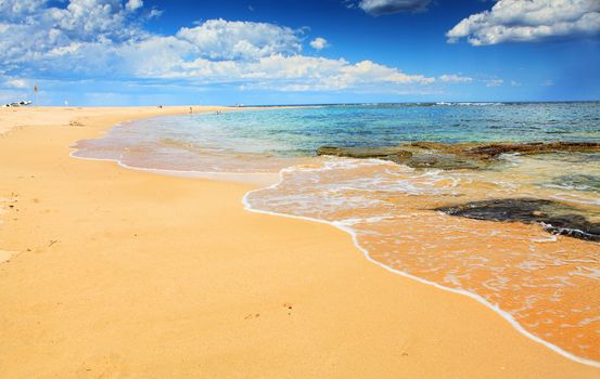 Beautiful unspoilt beach, known as Little Bay, near Sydney Australia, on a beuatiful summer day.  Motion in the water.  People have been blurred,