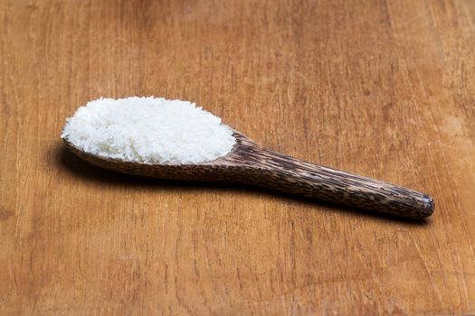 rice on wooden ladle on brown wooden plate