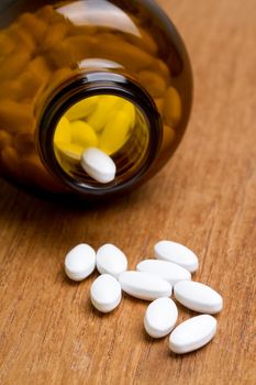 white pill with bottle on wooden plate