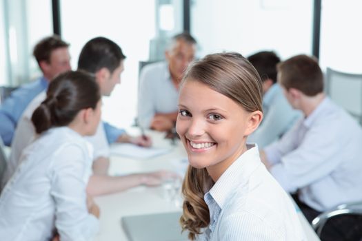 Portrait of a smiling young business woman with her team in the background 