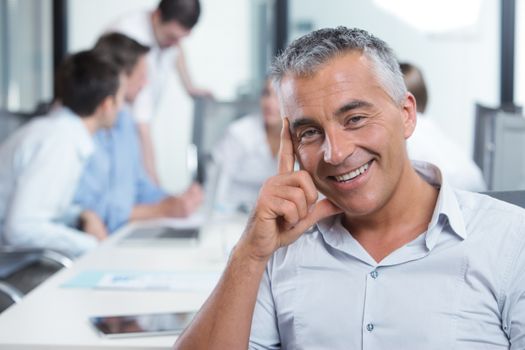 Portrait of a handsome businessman, blurred colleagues in the background 