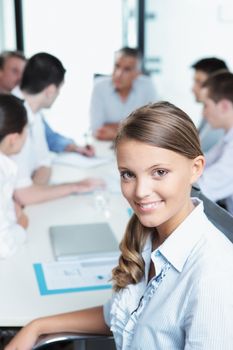 Portrait of a pretty young executive with her team in the background 