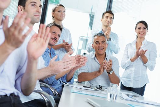 A group of happy business people clapping in a meeting