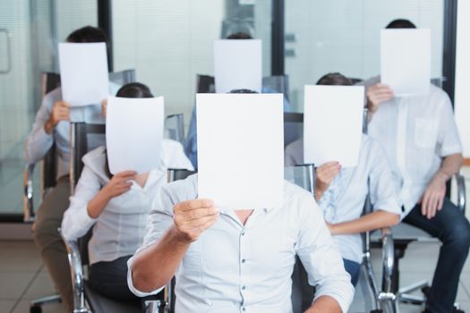 A group of business people holding a blank placard in front of face 