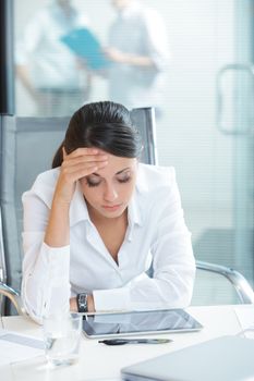 Young tired business woman with headache sitting  in workplace