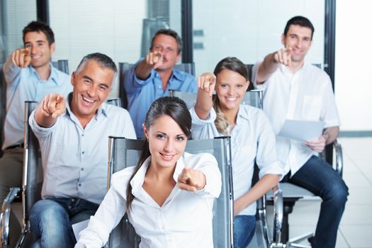 Portrait of a smiling business team pointing at you 