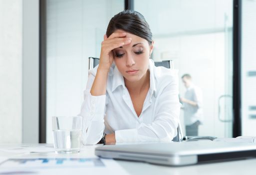 Young tired business woman with headache sitting  in workplace