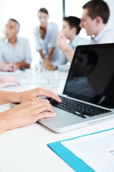 Group of business people working together, hands typing on laptop