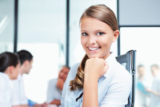 Portrait of a pretty young woman with her team in the background 