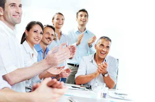 A group of happy business people clapping in a meeting