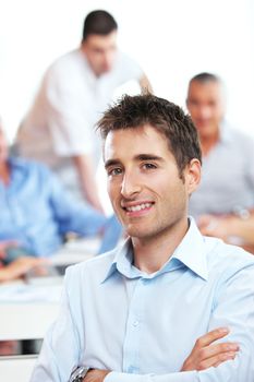 Portrait of a young businessman, blurred colleagues in the background 