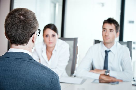 Two business people having job interview with young man