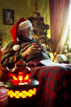 Pictures of Santa Claus relaxing at home, he holding a cup of tea