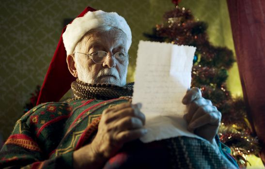 Portrait of a Father Christmas looking letters sent to him by children.