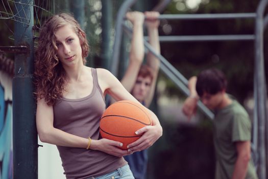 Teen Girl with basketball, her friends on the background
