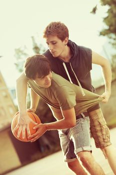 Boys playing a game of basketball on an outdoor court.