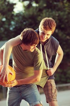 Two friends playing a game of basketball on an outdoor court.