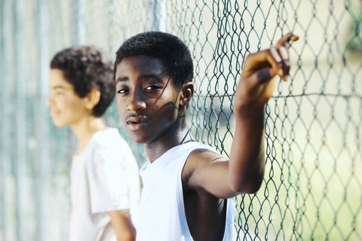 Young African boys  leaning up against a chain link fence