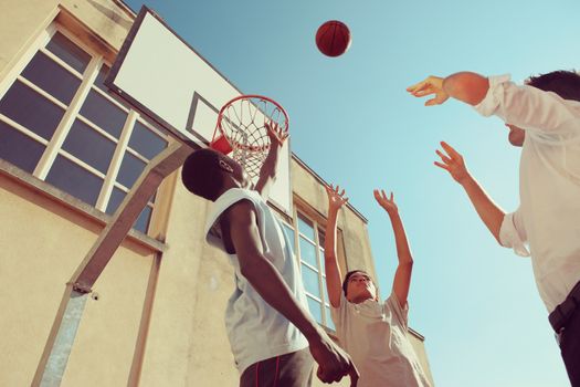 Two Afro-American boy and a man playing basketball