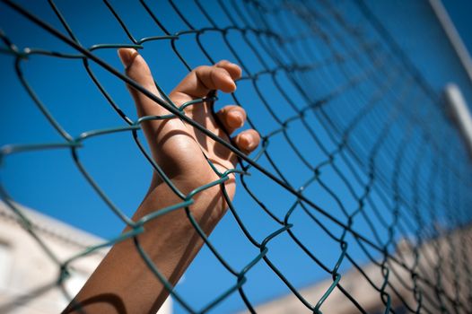 A boy's hand clinging on to a fence