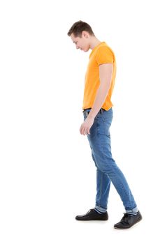 Young man, wearing a yellow T-shirt and slim jeans, standing on white background