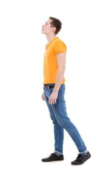 Young man, wearing a yellow T-shirt and slim jeans, standing on white background