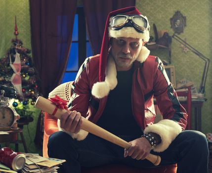 A frowning Bad Santa with baseball bat looking at camera