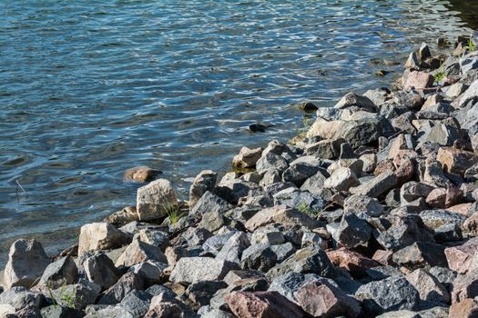 Pile of rocks at lakeside forming a natural beach