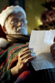 Portrait of Father Christmas sitting in armchair reading letters