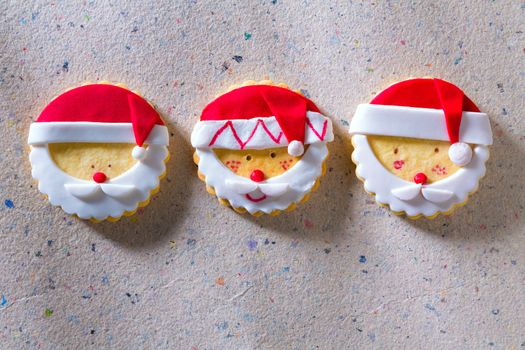 Christmas cookies with santa face in a row on recycled paper background