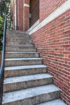cement stairs next to brick wall with metal railing