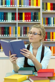 Portrait of clever student with open book reading it in library