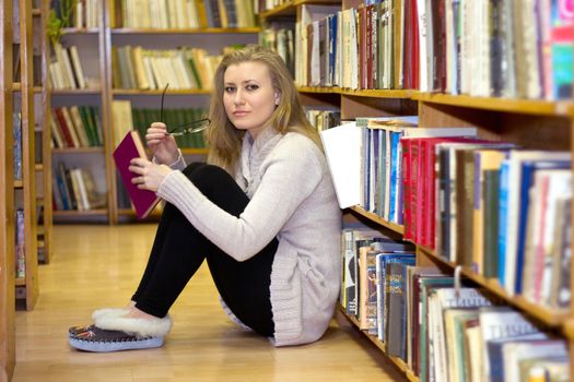 Girl sitting on the floor in the old library of books