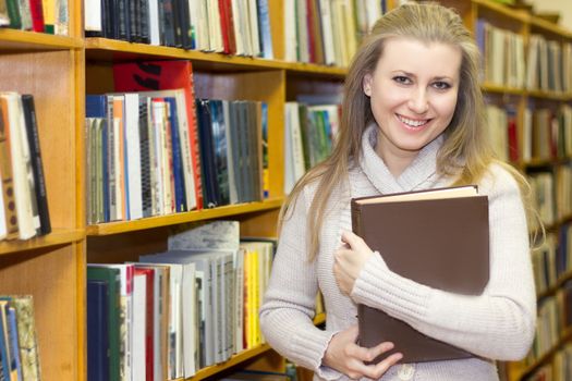 female student standing at bookshelf in old library searching for a book.