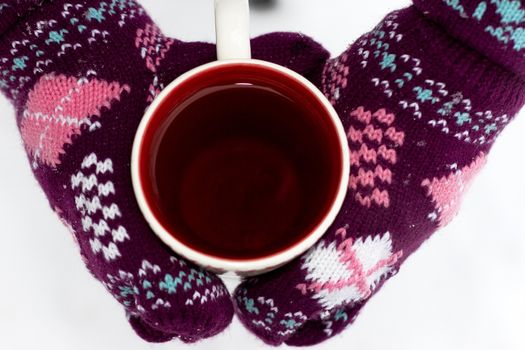 Cozy red gloves hold a mug of hot cocoa on a snowy day