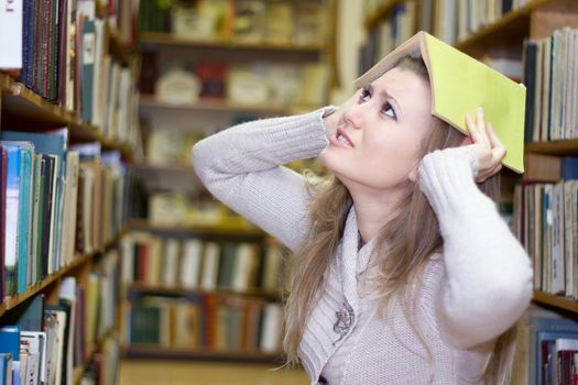 female student standing at bookshelf in old library searching for a book.