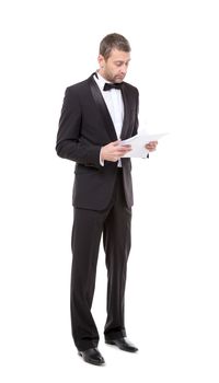 Stylish middle-aged man in a bow tie and tuxedo reading the document in his hand