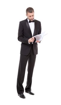 Stylish middle-aged man in a bow tie and tuxedo reading the document in his hand
