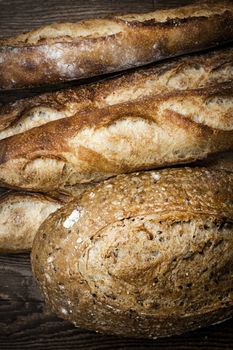 Fresh baked rustic bread loaves on dark wood background